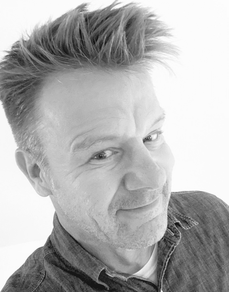 Man smiling in black and white photo.